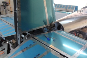 The vertical stabilizer is clamped to the horizontal stabilizer's forward spar and to the rear bulkhead of the fuselage.